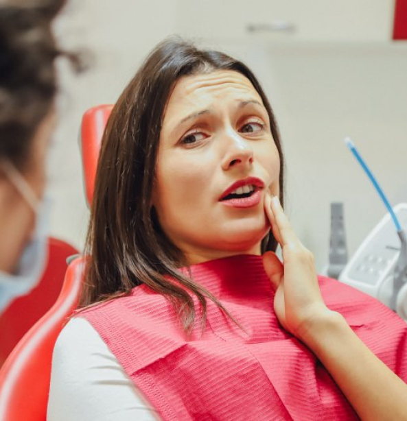 Patient in dental chair experiencing tooth sensitivity or discomfort during examination.