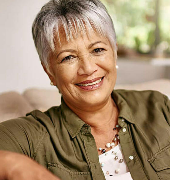 Smiling woman with short gray hair wearing olive jacket, representing Portland dental practice team.