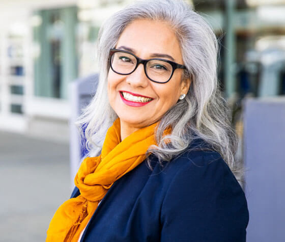Woman with gray hair and glasses smiling at Portland dental practice.