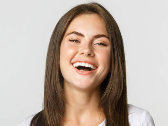 Woman smiling brightly, displaying healthy teeth and a confident expression.
