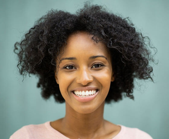 Smiling woman with natural curly hair in Portland dental office setting.