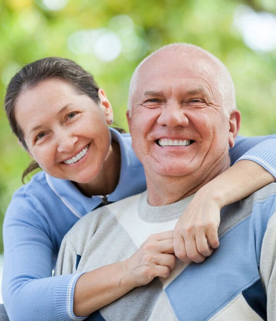 Happy middle-aged couple smiling outdoors in Portland, OR dental practice.
