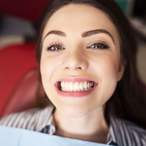 Smiling woman with bright white teeth after successful dental crown treatment in Portland.