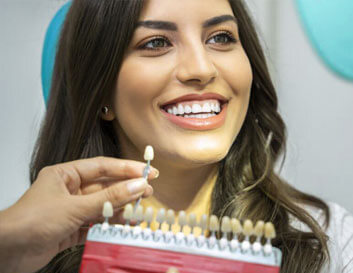 Woman holding a dental shade guide and smiling, showing cosmetic dentistry results in Portland.