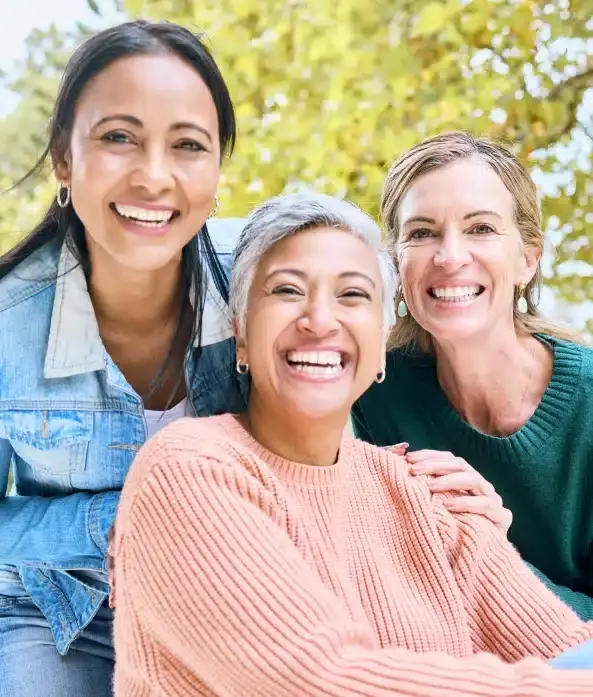 Three smiling women of different ages posing together outdoors in Portland.